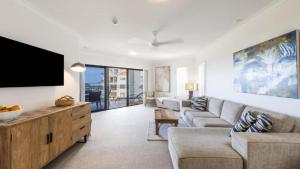 a living room with a couch and a flat screen tv at The Breakers Yamba in Yamba