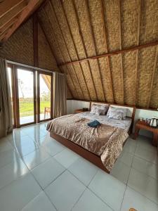 a bedroom with a bed and a large window at Surya Camp Buahan in Kubupenlokan
