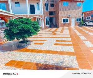 a tree in front of a building with a tile floor at kimkeri hotel in Ogbojo