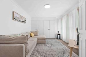 a white living room with a couch and a rug at Casa LuCe by Experience Jervis Bay in Erowal Bay