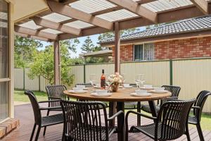 a wooden table and chairs on a wooden deck at Casa LuCe by Experience Jervis Bay in Erowal Bay