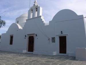a white church with a steeple and two doors at Anima Apartments in Chora Folegandros