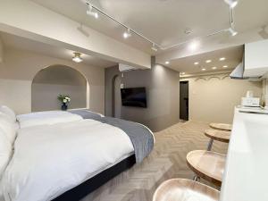 a bedroom with a large white bed and a kitchen at Clio Matoba by b hotel - Fully Equipped Studio 10min to Hiroshima Station in Ōsukachō