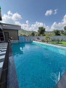 a swimming pool with blue water in front of a building at Hill Touch Villa in Thūr +4 photos