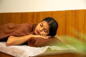 a woman laying on a bed with her head at Eeleem Resorts and Spa, Munnar in Anachal