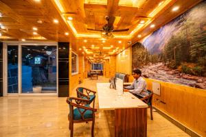a man sitting at a desk in front of a computer at Vedikant Pine Tree Resort in Chail