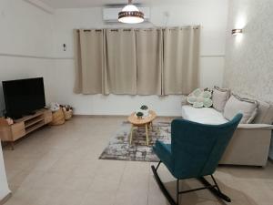 a living room with a blue chair and a television at Bertha's Coffee in Afula