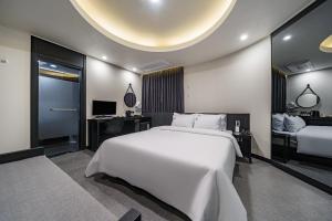 a bedroom with a large white bed and a desk at Daejeon Brown Dot Wolpyeong in Daejeon