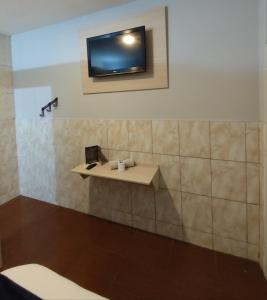 a bathroom with a sink and a tv on the wall at Hotel Anoitecer - 100 metros metrô Carandiru, 700 metros Rodoviária do Tietê, 900 metros Aeroporto Campo de Marte, 1,4 km Expor center norte, 1,8 km Distrito do anhembi! Oferecemos como cortesia café da manhã e estacionamento! in São Paulo