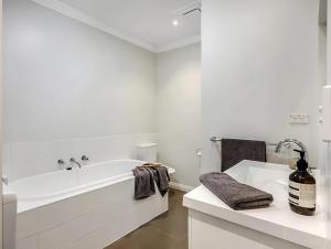 a white bathroom with a tub and a sink at Hobart Central Retreat in Hobart
