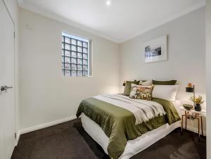 a white bedroom with a bed and a window at Hobart Central Retreat in Hobart
