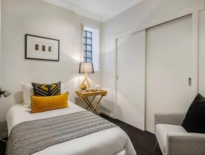 a bedroom with a bed and a chair and a window at Hobart Central Retreat in Hobart