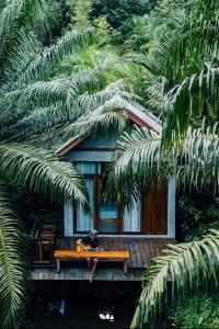 a man sitting on a bench in front of a house at BaanRaiChayKhaoFarmStay in Nakhon Si Thammarat
