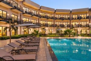 a hotel with a swimming pool and chairs and a building at Ramada by Wyndham Sonipat Murthal in Sonīpat