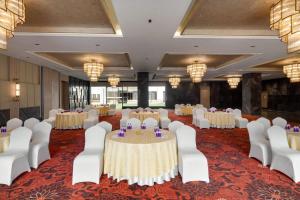 a banquet hall with tables and chairs and chandeliers at Ramada by Wyndham Sonipat Murthal in Sonīpat +27 photos