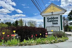 a sign for a golden gates inn with flowers at Golden Gables Inn Dazzler Select by Wyndham in North Conway