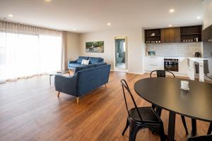 a living room with a blue couch and a table at Murchison View house with Jacuzzi in Te Anau