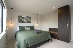a bedroom with a green bed and a wooden cabinet at Murchison View house with Jacuzzi in Te Anau