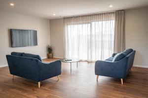 a living room with two blue chairs and a tv at Murchison View house with Jacuzzi in Te Anau