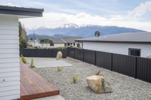 a backyard with a fence and a rock at Murchison View house with Jacuzzi in Te Anau