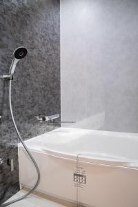 a shower in a bathroom with a white tub at 瓦町家kawaramachiya in Takamatsu