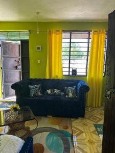 a living room with a blue couch and yellow curtains at ADONAI homes in Malindi