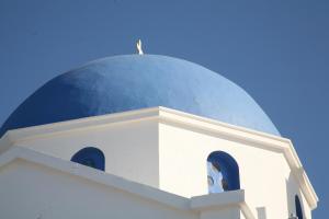 a white church with a blue dome on top at Anima Apartments in Chora Folegandros