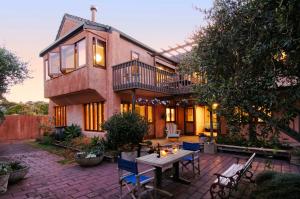 un patio con mesa y sillas frente a una casa en Orewa Beachside, en Orewa