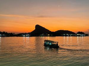 a small boat in the water at sunset at Sleep4cheap@Donsak in Don Sak