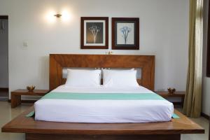 a bedroom with a large bed with a wooden headboard at Sandy Bliss Villa in Sri Jayewardenepura Kotte