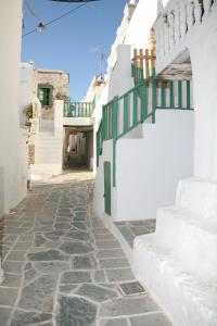 an alley with white buildings and a green railing at Anima Apartments in Chora Folegandros