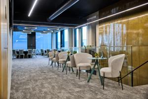 a row of tables and chairs in a room with windows at Kongres Hotel Roca in Košice