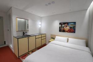 a bedroom with a large white bed and a sink at Fritta Hotel in Suwon