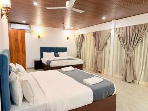 a bedroom with two beds and a ceiling fan at Orange Sky Inn in Canacona +29 photos
