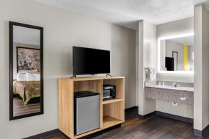 a hotel room with a television and a bathroom at Super 8 by Wyndham Evansville East in Evansville