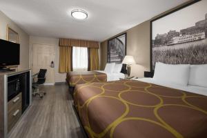 a hotel room with two beds and a flat screen tv at Super 8 by Wyndham Macon West in Macon
