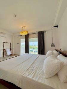 a bedroom with a large white bed with a window at Moringa Beach in Mirissa