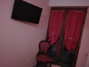 Habitación con silla y TV en la pared en appartamento via san pardo, en Matera