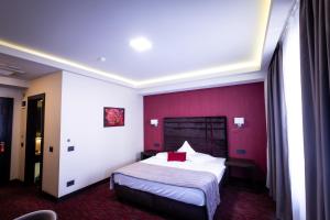 ein Hotelzimmer mit einem Bett und einer roten Wand in der Unterkunft Old Town Hotel in Timişoara