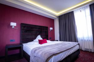 ein Schlafzimmer mit einem großen Bett und einer roten Wand in der Unterkunft Old Town Hotel in Timişoara + 51 Fotos