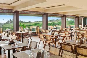 a restaurant with tables and chairs and windows at Amaari Beach Resort in Kanyakumari