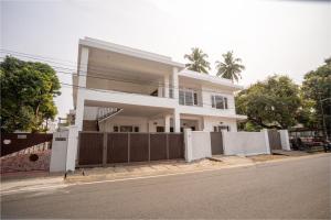 a white house with a fence on a street at Orma in Cochin