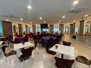 a restaurant with tables and chairs and a tv at Hotel Desaru Penawar in Desaru