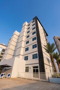 a tall white building with a palm tree in front of it at The Luxe Retreat Hotel Apartments in Dubai