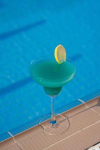 a drink in a martini glass next to a pool at The Luxe Retreat Hotel Apartments in Dubai