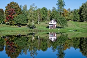 a house on a hill next to a lake at Atpūtas vieta Upes Sausītes in Sidrabiņi