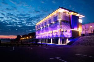 a building with purple lights on the side of it at Hotel Navis in Orašje