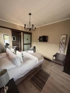 a bedroom with a large white bed and a chandelier at Amru Guesthouse B&B in Brackenfell