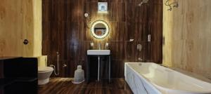 a bathroom with a tub and a sink and a mirror at The HighGarden Resort in Udaipur