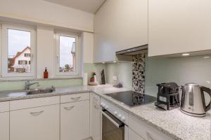 a kitchen with white cabinets and a sink at Cocoa Suite · Kilchberg in Kilchberg